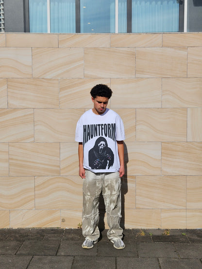Person wearing a white t-shirt with a graphic design on a tiled pavement.